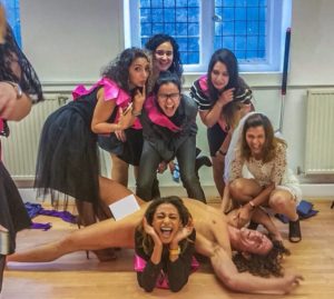 A life model poses on his back on the floor at a life drawing hen party activity.